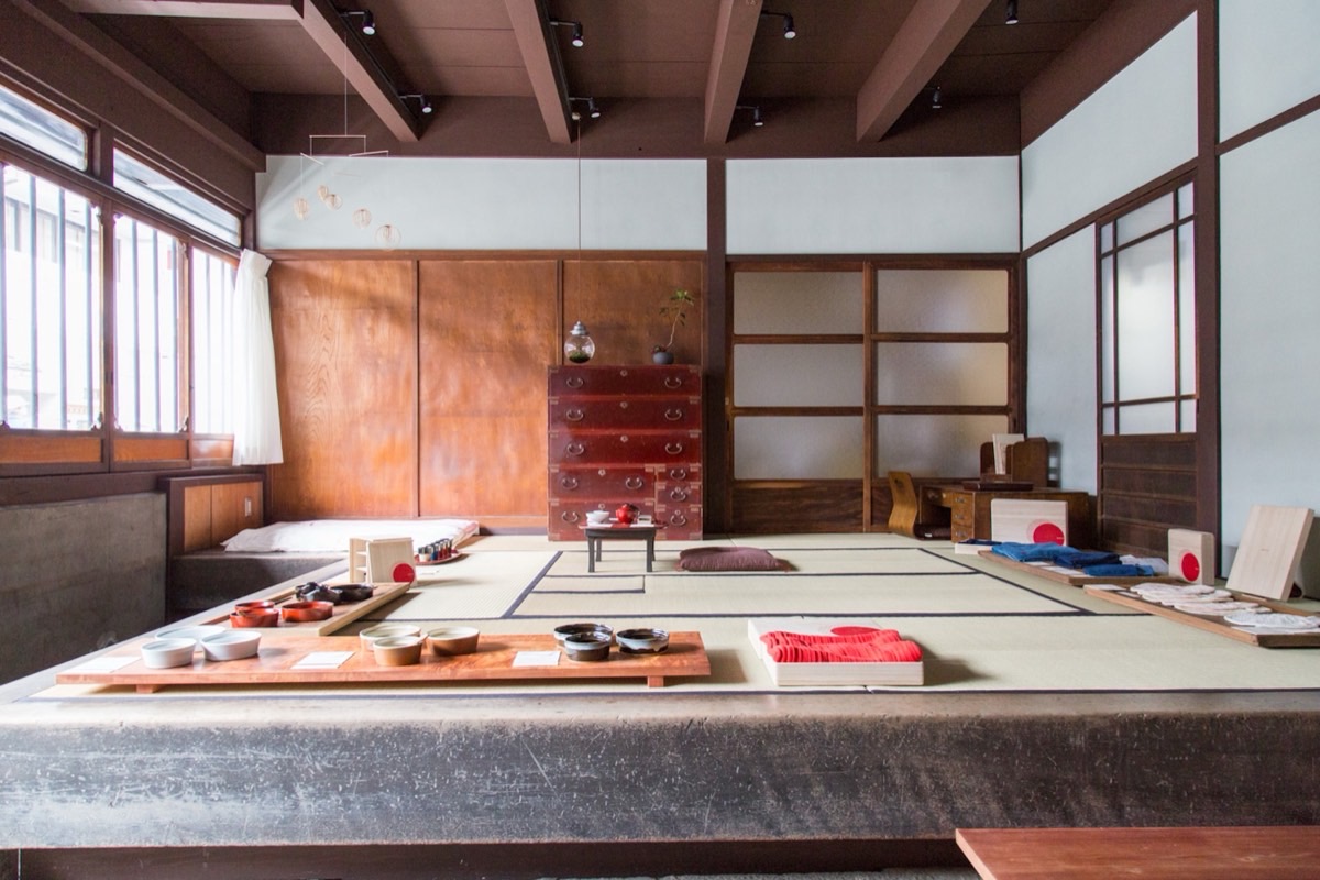 The tatami room at aeru gojo, with a red tansu chest, low tables of tea bowls, and light from the street windows.